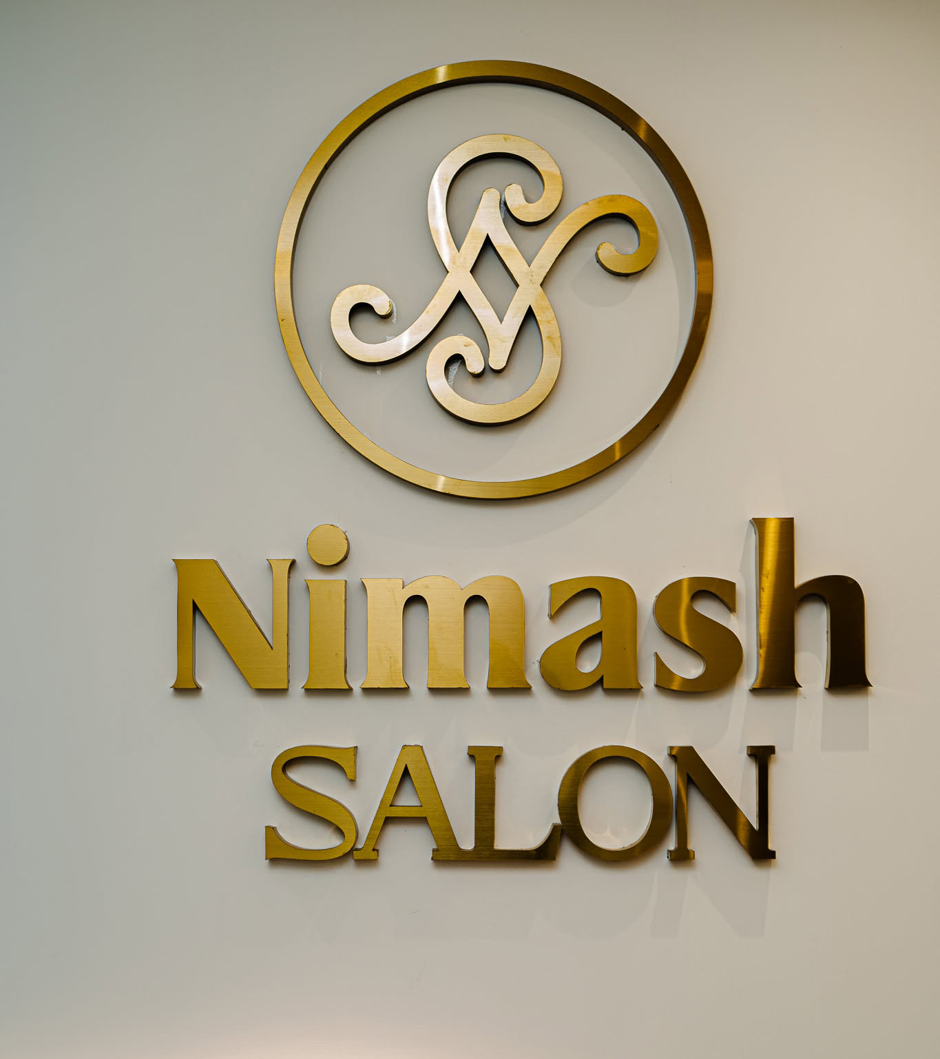 Nimash Salon gold monogram logo on wall